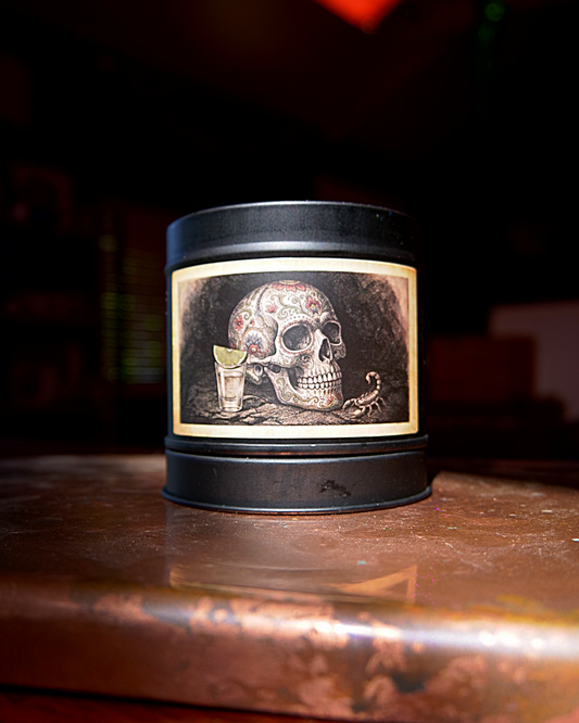 Mexican Tequila Bar candle in a matte black tin, lid on, with an etched label of a decorated calavera beside a tequila shot and lime — Wayward