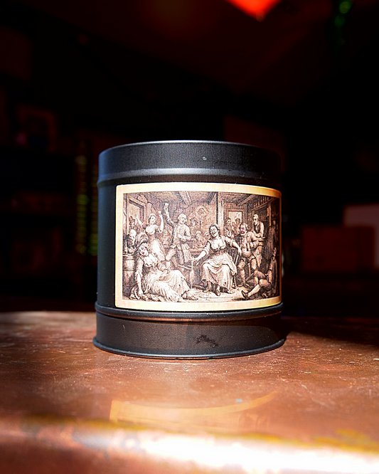 Victorian Gin House candle in a matte black tin, lid on, with an etched label of a riotous gin-house interior — Wayward