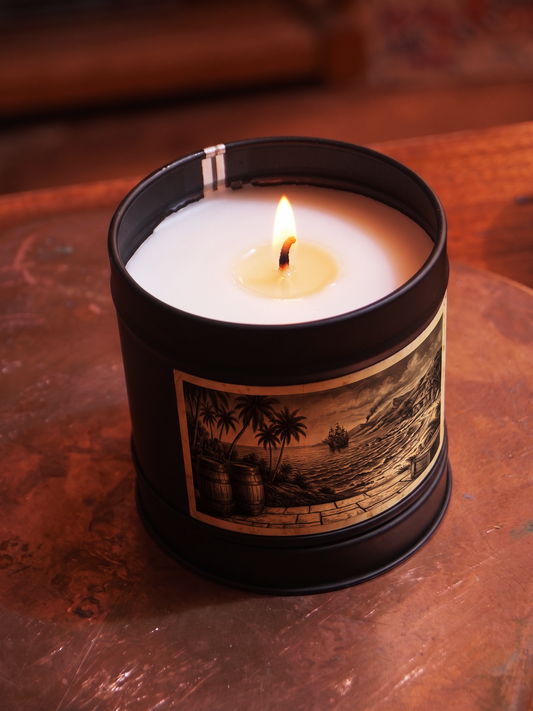 Caribbean Rum Shack scented candle by Filthy Candles, lit in a black tin with tropical harbour illustration