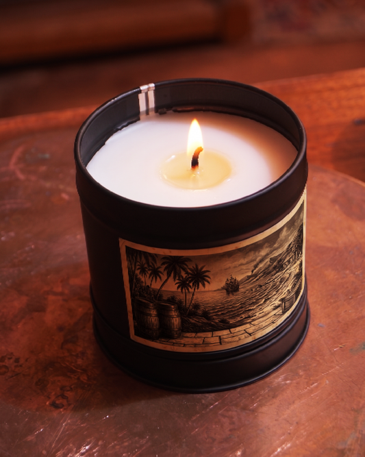 Caribbean Rum Shack candle burning, wax pooled to the edges, the etched barrels and shoreline label lit from above — Wayward