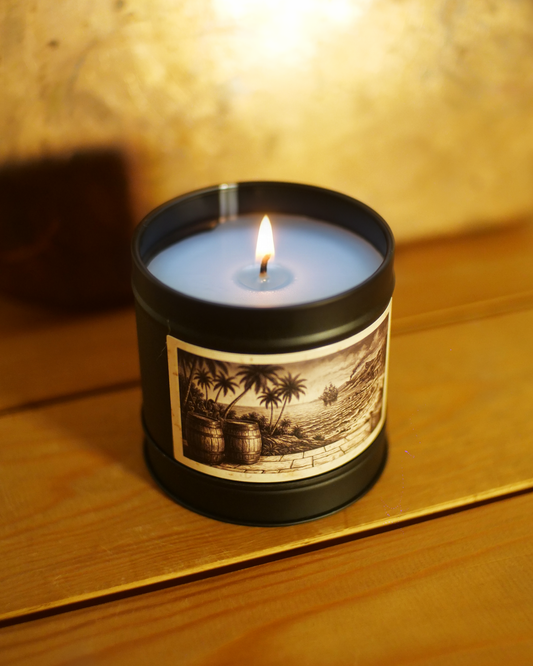 Caribbean Rum Shack candle burning, wax pooled to the edges, the etched barrels and shoreline label lit from above — Wayward